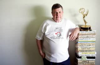John Hill stands next to his life's work, about 70 scripts and novels written over the past 38 years, inside his Las Vegas home Wednesday, May 6, 2009. Hill won the Emmy in 1991 for his work on 