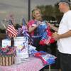 Robin Reese hands Craig Corey, right, an American flag outside the Boulder Dam Credit Union while collecting donations and selling T-shirts for the Damboree fireworks display in 2009. For 20 years, Reese, also known as the "Jug Lady," decorated water jugs and placed them around town, helping to raise money for the Fourth of July celebration.