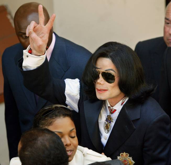 Michael Jackson flashes the "V sign" to the crowd as he exits the courthouse in Santa Maria, Calif., on Jan. 16, 2004, for his arraignment on child molestation charges. Jackson's sister Janet hugs a supporter at bottom.
