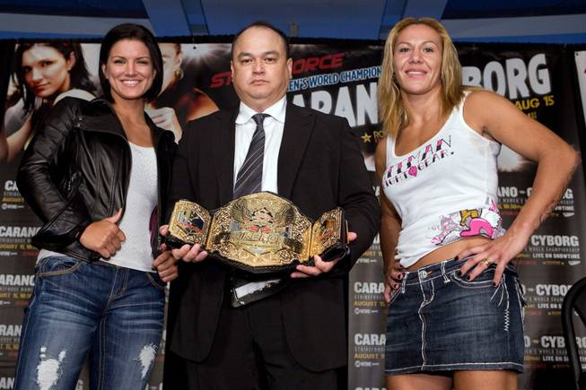 Strikeforce chief Scott Coker, center, holds the 145-pound women's title belt that was up for grabs between Gina Carano, left, and Cristiane "Cyborg" Santos. Santos won the fight.