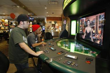 Joe Carrera, left, and Brandon Edmon of San Pedro, Calif. play Texas Hold’em with an animated dealer in the Gold Spike’s remodeled casino floor in downtown Las Vegas Monday, Aug. 17, 2009. 