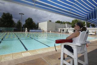 Lifeguard Shelby Gebhart watches over a deserted pool as rain droplets fall Saturday during closing day at the Boulder City Pool.