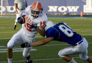 Bishop Gorman wide receiver Michael McRea takes a hit from Dixie cornerback Tanner Mitchell Friday in St. George, Utah.