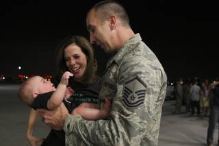 Master Sgt. Shaun Davis holds his 5-month-old son, Tommy, as his wife, Kristy, sheds tears beside them during a welcome-home celebration Sunday night at Nellis Air Force Base.