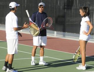 Adam Yee, center, serves as father and coach to local tennis phenoms Kristofer, left, and Kimberly, seen here conversing after a practice session at Lorenzi Park on Monday afternoon.