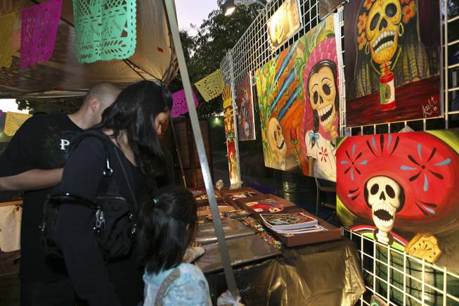 From left, Alex Zamora, Alicia and Priscilla Vasquez, 5, admire the oil and acrylic paintings by Joel Tirado for sale during the annual Life in Death: Day of the Dead Festival Sunday night at the Winchester Cultural Center and Park.
