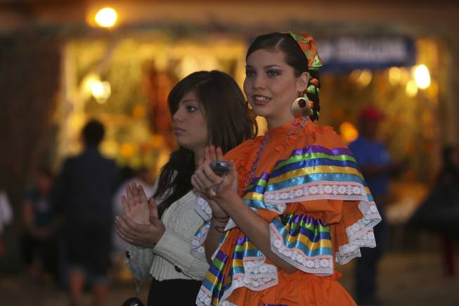 Wearing an authentic Mexican dress, Nancy Paz, 15, and her sister, Blanca, 17, applaud a Mexican dance troup performing Sunday night at the annual Life in Death: Day of the Dead Festival at the Winchester Cultural Center and Park.