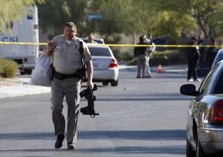 A Metro Police officer carries a bag and a police utility belt as he leaves the area of a crime scene and carries the items to a patrol car in North Las Vegas Thursday, Nov. 19, 2009.  