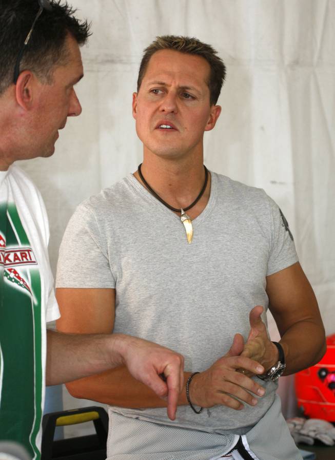 Seven-time Formula One World Driving Champion Michael Schumacher talks with a team member.