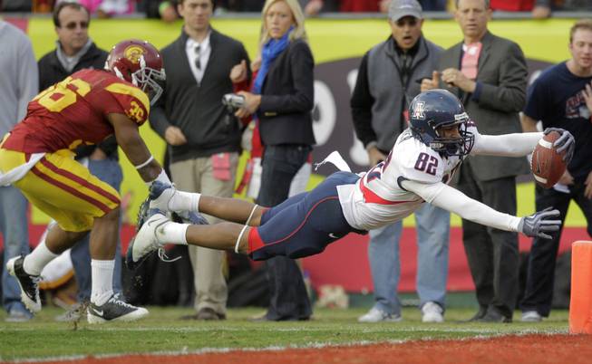 Arizona wide receiver Juron Criner, right, dives into the end zone to score a touchdown against Southern California during the second half of their NCAA college football game in Los Angeles, Saturday, Dec. 5, 2009. At left is USC's Josh Pinkard. Arizona won 21-17. 