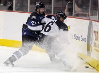 Wranglers defenseman Robbie Bina attempts to throw on the brakes while being shoved toward the boards by Steelhead winger John Swanson during the annual midnight game at the Orleans Arena on Tuesday night.