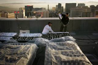 Pyrotechnicians Jim Stannard, left, and Carlton Siple from Fireworks by Grucci, a company based in Long Island, New York, put aluminum foil over the fireworks that are part of the finale for New Year's Eve on the roof of Treasure Island in Las Vegas Wednesday, December 30, 2009.