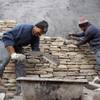 Oscar Rugamas, left, and Elmer Lara of Alvarez Masonry place stones on the exterior of a New American Home on Jan. 8 at 2911 Bella Kathryn Circle. Lack of financing for the project, which was supposed to be completed for next week's International Builders' Show, helped drive builder Domanico Custom Homes out of business.