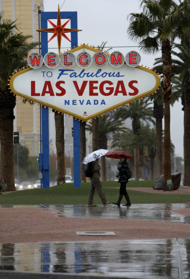 Remo Wuerth, left, and Sibylle Heinemann, tourists from Switzerland, chat in the rain after taking a bus to the "Welcome to Fabulous Las Vegas" sign Thursday, Jan. 21, 2010.