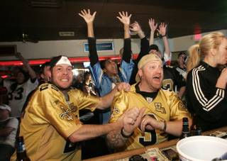 Saints fans Seth Russell, left, and Josh Lewis cheer with the rest of the 7-11 Bar and Grill as the New Orleans Saints tied the Minnesota Vikings late in a game on Jan. 24.