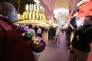 Jeff Keen, left, of St. Louis poses for a photo taken by Scott Sheen, right, who is trying to sell him the large Mardi Gras beads Keen is wearing, during Fat Tuesday celebrations at the Fremont Street Experience in downtown Las Vegas Tuesday, February 16, 2010.