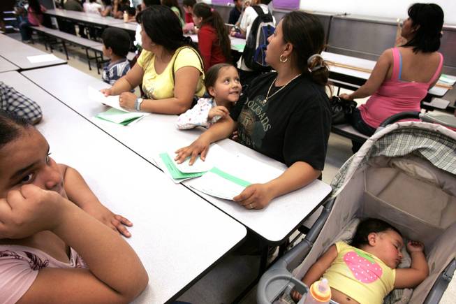 Denise Moreno, from left, 4, looks up at her mother Maria Moreno as her other daughter, one-year-old Sitlally Moreno dozes nearby during math night at Herron Elementary School in North Las Vegas Wednesday, March 24, 2010.
