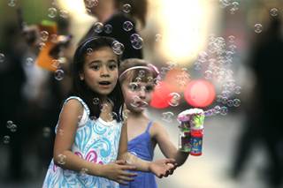 New friends Mikayla Benitez (L) and Eden Fuller play with a bubble gun Saturday during the annual Helldorado Parade.