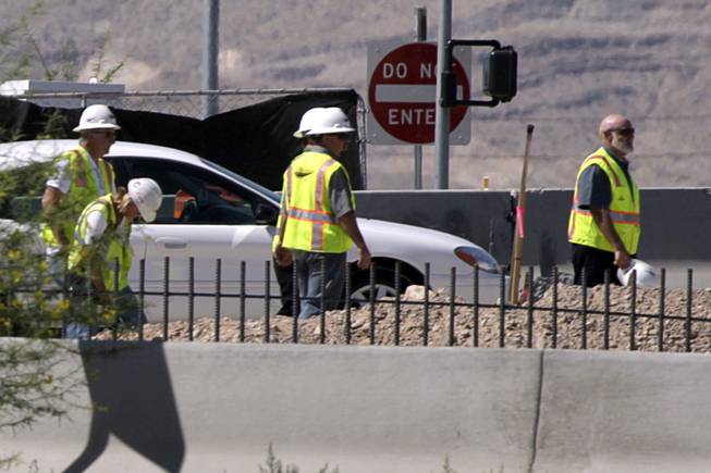 Workers wait as officials investigate a fatal construction accident on Blue Diamond Road by the I-15 northbound on-ramp Tuesday, June 29, 2010.