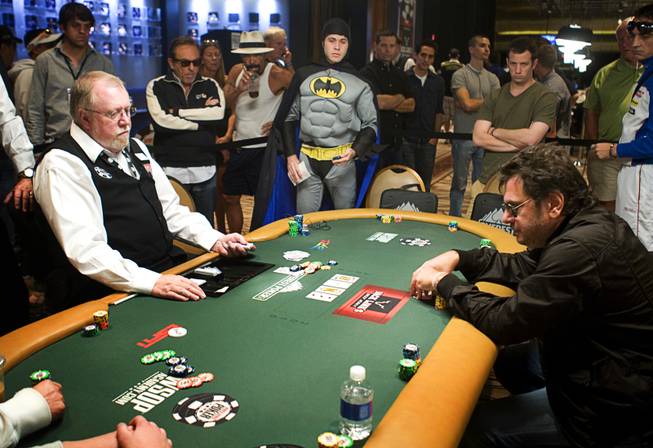 Canadian medical student Phil Dwek, center, dressed as Batman, watches as players at his table finish a hand before a break during the 41st annual World Series of Poker Main Event on Tuesday at the Rio.