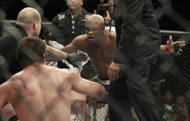 Anderson Silva, center, celebrates in front of Chael Sonnen after submitting Sonnen in the fifth round during a middleweight championship fight at UFC 117 on Saturday in Oakland, Calif. Silva retained his championship.
