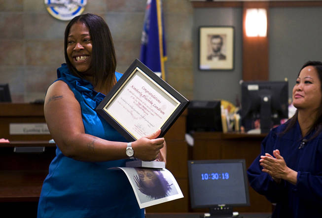 Kimberly Landrum displays her certificate of graduation to friends and family as she graduates from WIN (Women in Need), a city of Las Vegas specialty court, Tuesday at the Regional Justice Center. Las Vegas Municipal Court Judge Cynthia Leung applauds at right. Landrum has a criminal history that began in 2000, with charges ranging from embezzlement to drugs, credit card fraud and prostitution. Today, she has successfully completed her recovery programs, is employed and is an inspiration to other program participants.