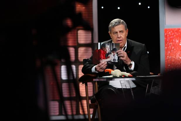 Surrounded by video cameras, Jerry Lewis shows the television audience ...