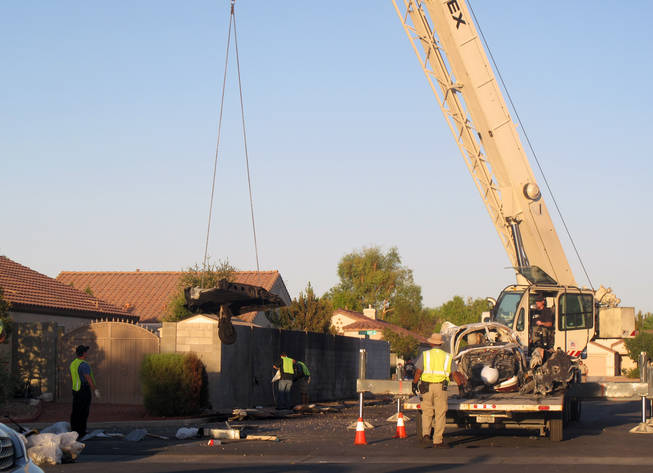 A crane and flatbed truck arrive at the scene around 6 p.m. Monday to begin cleaning up debris on Morning Mauve Avenue. The wreckage will be taken to a secure location where the National Transportation Safety Board will continue its investigation.