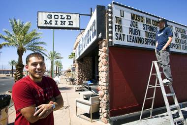 Bar manager Jose Rivera, left, and bartender Nathan Rincon update the Gold Mine Tavern’s sign last week on Water Street in Henderson.