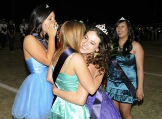 Coronado Homecoming Queen KaitlynThompson, right center, gets a big hug from Glory Finnegan as they celebrate during halftime festivities of the game between the Cougars and visiting Gators on Friday night. At left is Kiki Posner and at right is Kathy Chao.