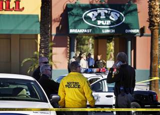Metro Police officers wait outside during an officer-involved shooting investigation at the P.T.'s Pub near Nellis Boulevard and Sahara Avenue on Monday, November 15, 2010. Three Metro Police officers shot and killed a man inside the tavern as the man was holding a bartender at knifepoint during a robbery attempt, police said.