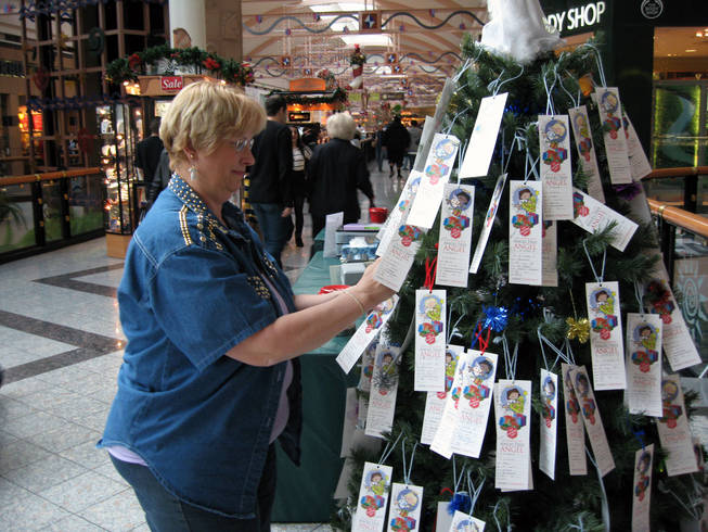 Bonnie Harmon arranges gift tags Saturday on the Angel Tree inside the Galleria at Sunset mall in Henderson. The Salvation Army asks people to pick a gift tag, buy the gift and return it to the organization, which will deliver it to a needy child for Christmas.