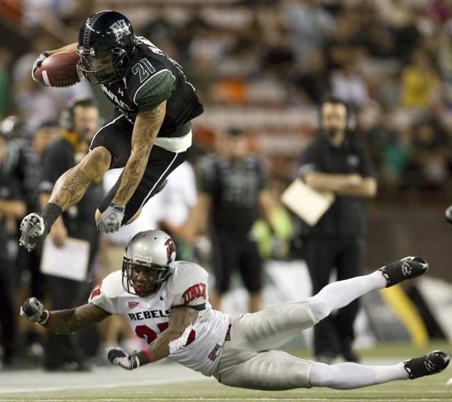 Hawaii slotback Kealoha Pilares leaps over UNLV defensive back Mike Grant during the first quarter of Saturday's game at Aloha Stadium in Honolulu.