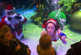 One of Santa's helpers puckers up for a kiss as children visit with an underwater Santa Claus swimming in a 117,000-gallon aquarium at the Silverton hotel-casino. Santa was equipped with a microphone so that he could communicate with the children. 