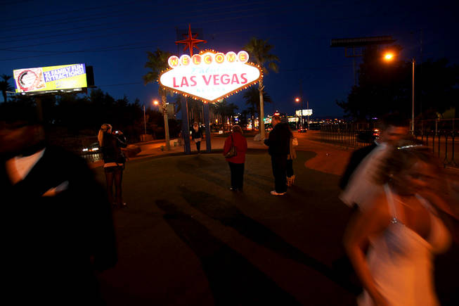 A newlywed couple leaves as people wait their turn to get photos at the "Welcome to Fabulous Las Vegas" sign on New Year's Eve 2010.