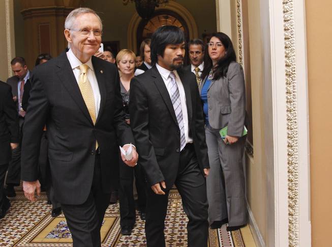 Senate Majority Leader Harry Reid of Nev., left, walks with Filipino Congressman and eight-time world champion boxer Manny Pacquiao on Capitol Hill in Washington, Tuesday, Feb. 15, 2011. 
