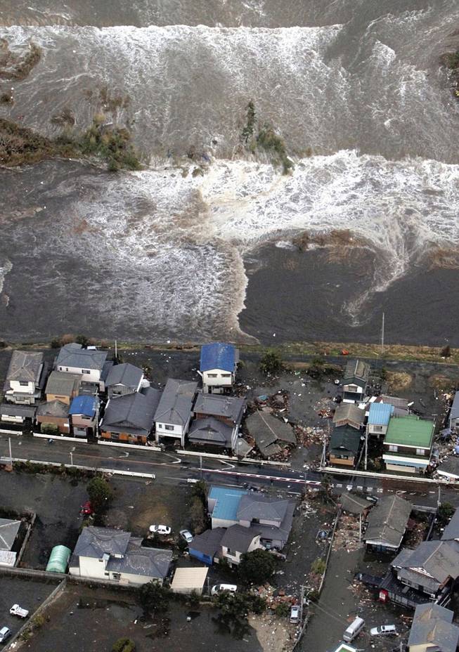 A tsunami approaches seashore houses in Kita Ibaraki, Ibaraki Prefecture, northeast of Tokyo, Friday, March 11, 2011.