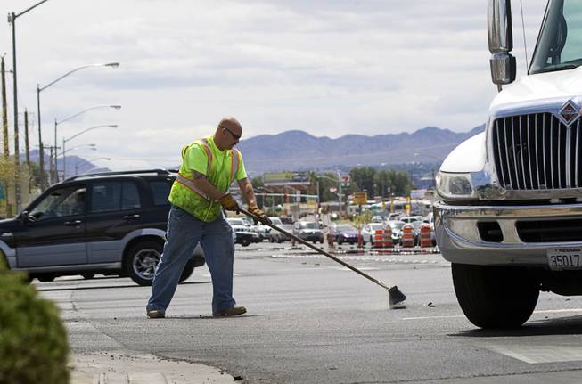 A Ewing Bros. tow operator sweeps up debris after an accident at Boulder Highway and Tropicana Avenue, May 17, 2011.