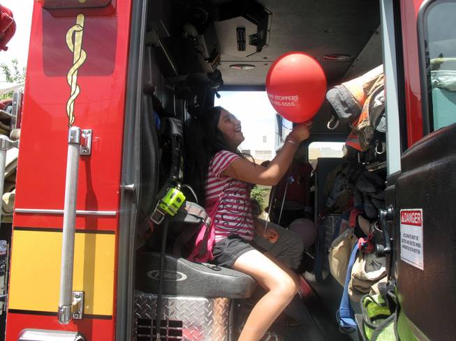 Marina Avila plays inside a fire truck with a Crime Stoppers balloon she got from a Metro Police officer Saturday at a block party and safety fair sponsored by Metro in downtown Las Vegas.