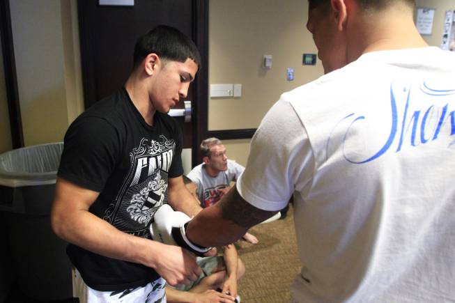 Sergio Pettis helps put on his brother Anthony Pettis' gloves during workouts for the TUF Season 13 fight card Thursday, June 2, 2011.