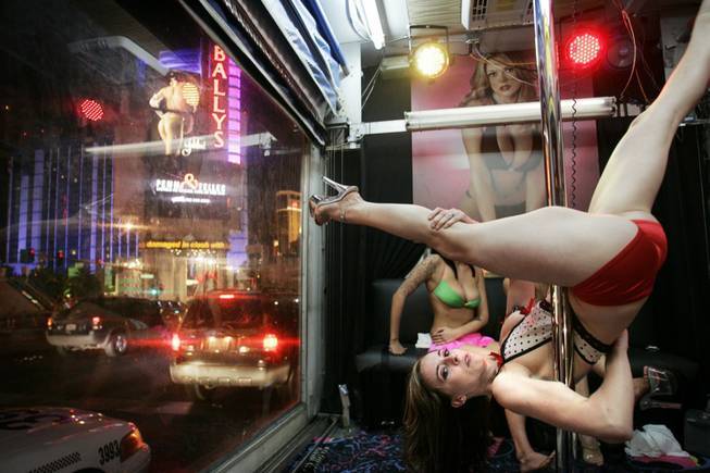 Kay from Deja Vu Showgirls performs on a pole with other strippers from Little Darlings while inside a truck with plexiglass walls used as an advertisement for strip clubs on the Strip late in the evening Monday, Nov. 9, 2009.