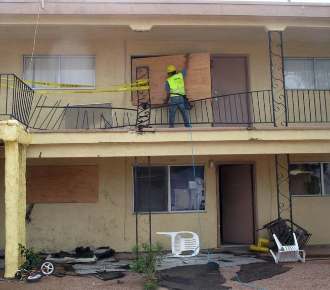Crews board a window shattered by a metal railing Sunday afternoon at the Willow Gardens apartment complex on Vegas Drive. Heavy rain and strong winds slammed the railing into the apartment unit.