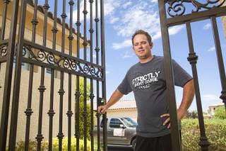 Steve Antill opens a security gate he built for a homeowner in Southern Highlands Monday, July 18, 2011. Antill, owner of Strictly Iron, started his business about a year ago after being laid off from the ornamental ironwork company where he was an employee.