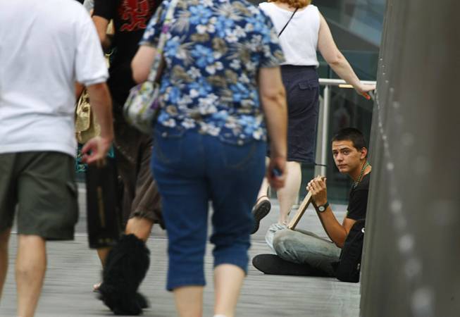 A man sits by a hand made sign asking for money on a pedestrian overpass on the Las Vegas Strip Sunday July 24, 2011.