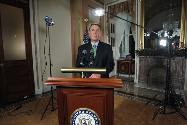 Speaker of the House John Boehner stands amid television lights at the Capitol after responding to President Obama's remarks about averting default and dealing with the federal deficit, in Washington, Monday, July 25, 2011.