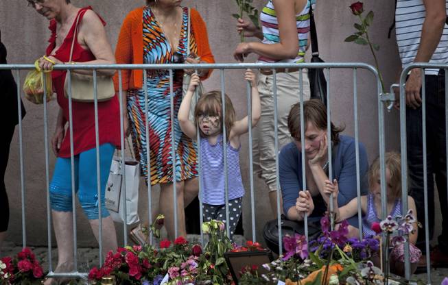 People look at tributes outside the Oslo Cathedral in Oslo, in memory of the victims of Friday's bomb attack and shooting rampage, Norway, Thursday, July 28, 2011. 