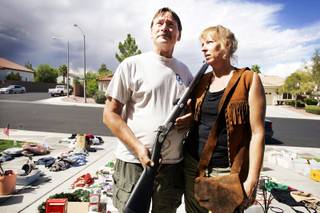 Steve Henderson with a black powder muzzleloader gun and his wife, Nellie, with a buckskin vest for sale at their driveway in Henderson on Saturday, Sept. 24, 2011.