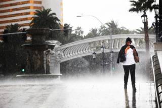 A woman walks during a downpour on the Strip outside the Venetian in Las Vegas on Monday, Oct. 3, 2011.