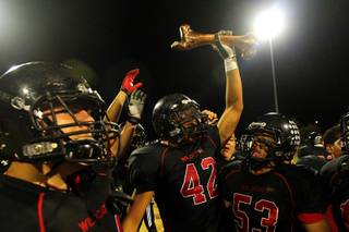 After beating Rancho 49-12, Las Vegas' Kaveo Walker holds the rivalry trophy, a bronzed cow bone, above his head Thursday, Oct.  20, 2011.