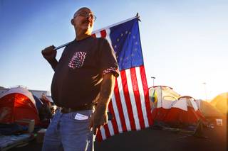 Mark Andrews of Las Vegas stands with an American flag with 13 colonies at Occupy Las Vegas between Paradise Road and Swenson Street south of East Naples Drive in Las Vegas on Thursday, Oct. 27, 2011.